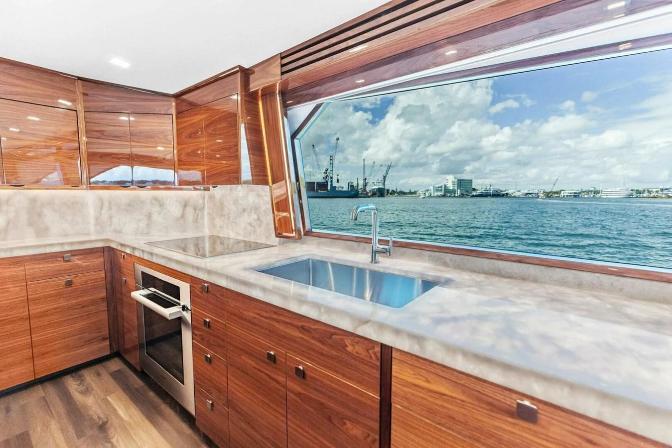The yacht's galley features sleek wooden cabinetry, a large window with a stunning view, and modern appliances. aboard TEAM HARVEY I Yacht for Sale