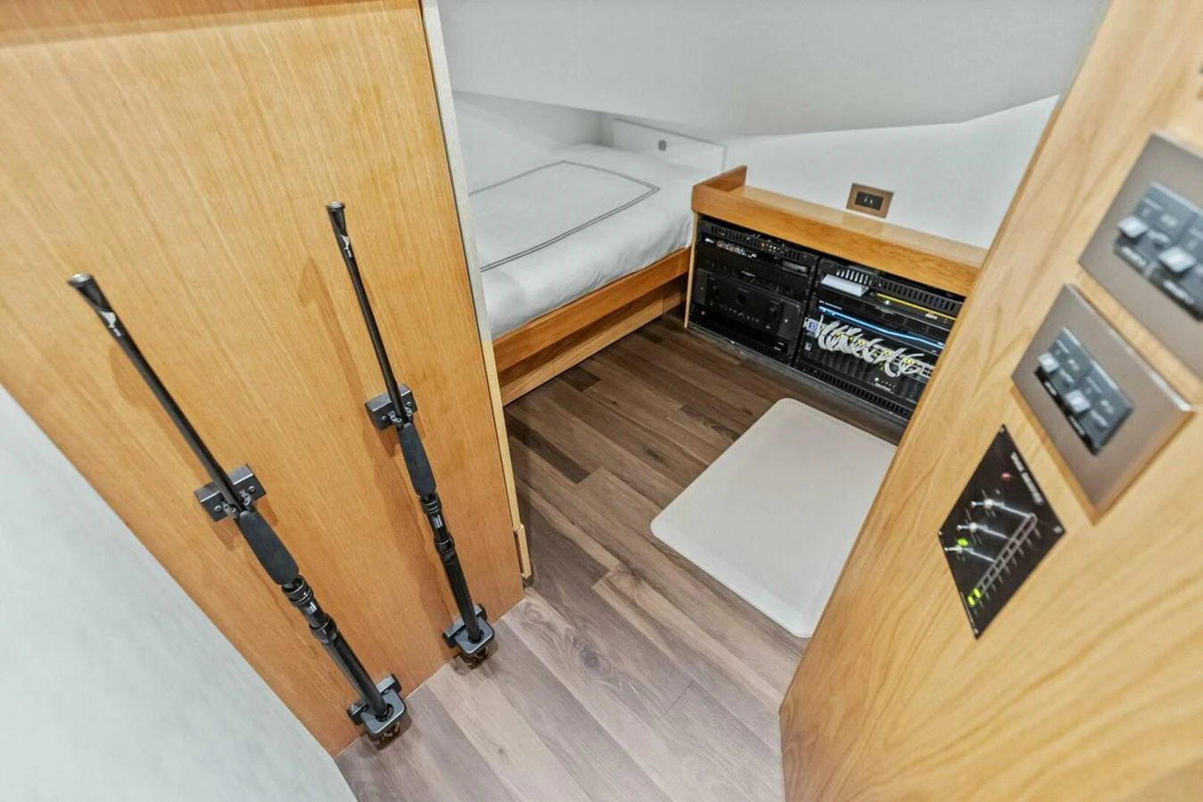A cozy interior space featuring a bed and storage compartments with fishing rods mounted on the door. aboard TEAM HARVEY I Yacht for Sale