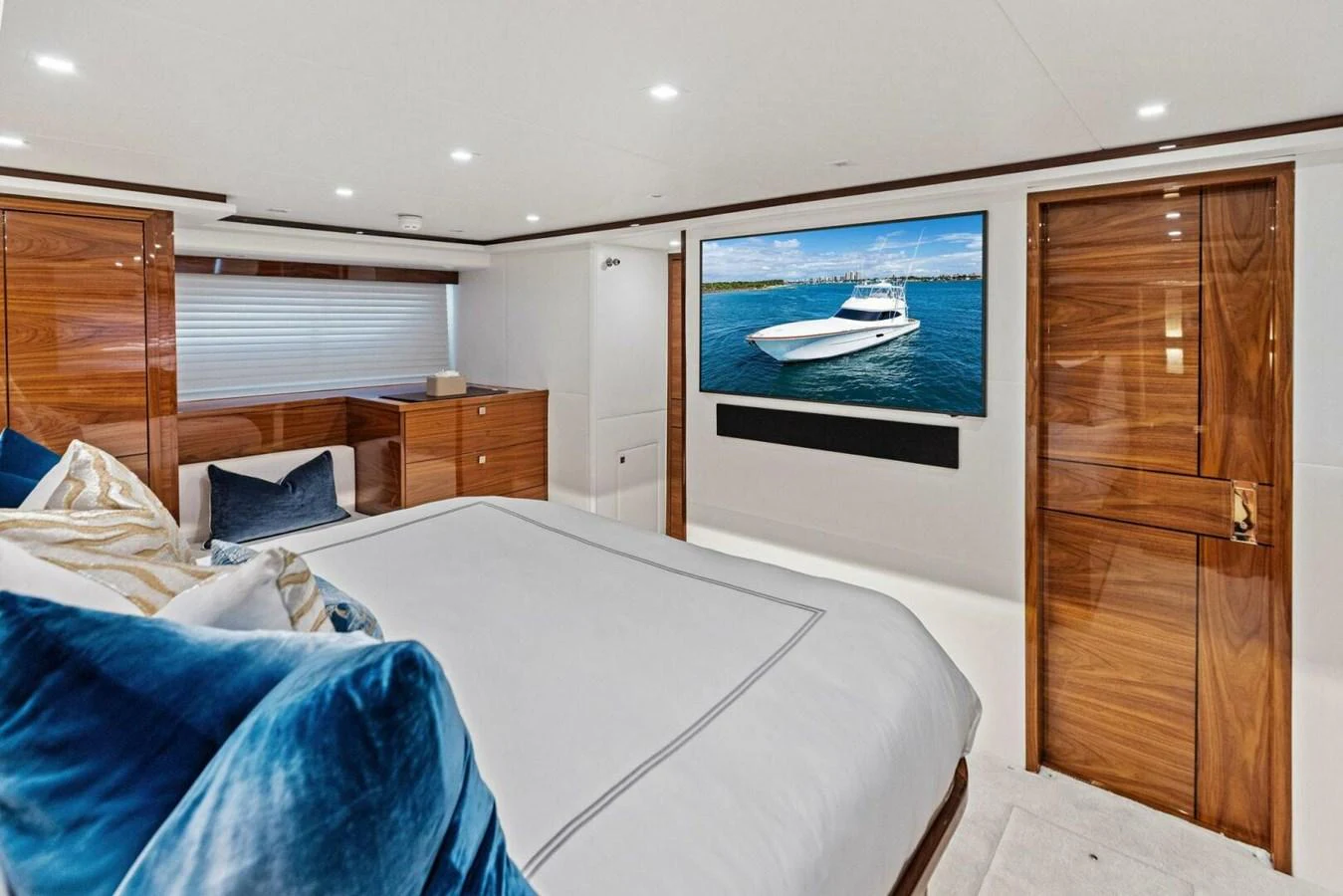 The master stateroom features a luxurious bed, elegant wood finishes, and a large TV screen. aboard TEAM HARVEY I Yacht for Sale