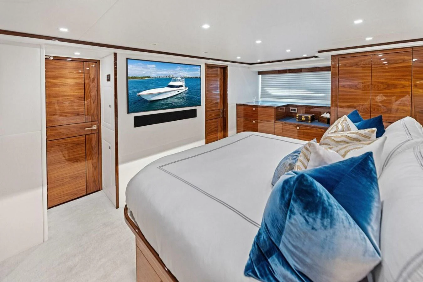 The master stateroom features a luxurious bed with plush pillows, elegant wood finishes, and a large flat-screen TV. aboard TEAM HARVEY I Yacht for Sale