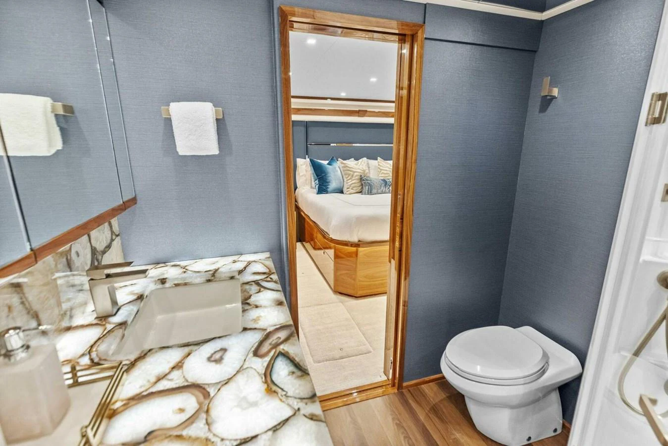 A luxurious yacht bathroom with a stylish sink, toilet, and a view into a cozy bedroom. aboard TEAM HARVEY I Yacht for Sale