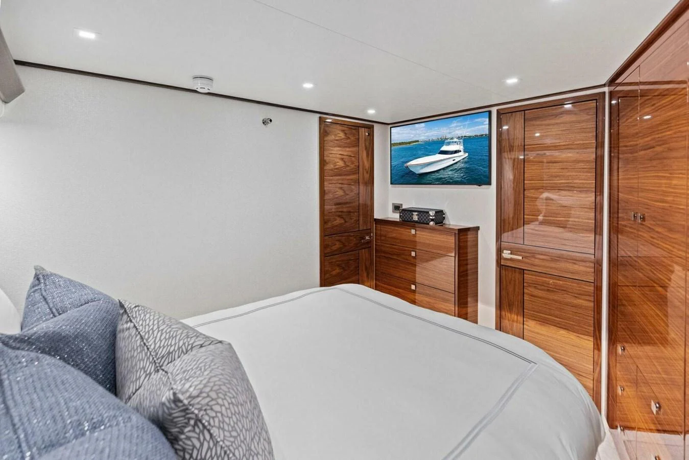 The stateroom features a luxurious bed with plush pillows and elegant wooden cabinetry, complemented by a flat-screen TV. aboard TEAM HARVEY I Yacht for Sale