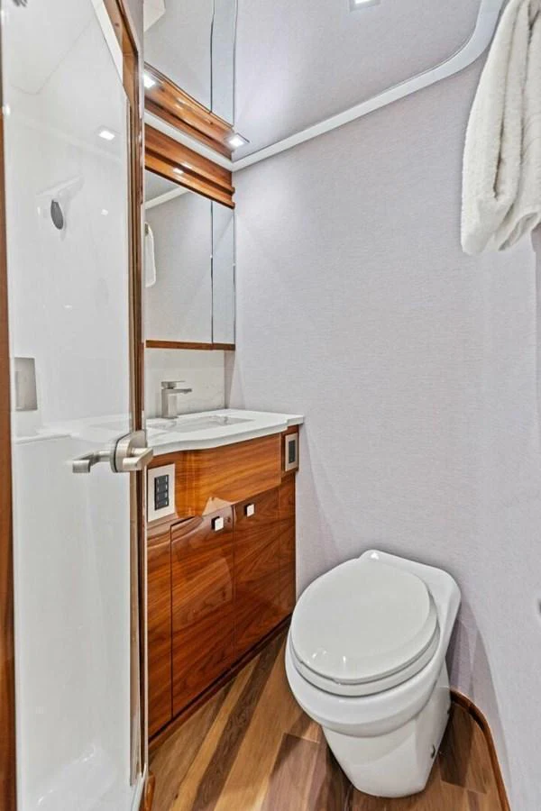 A sleek and modern yacht bathroom with wooden cabinetry and a glass-enclosed shower. aboard TEAM HARVEY I Yacht for Sale