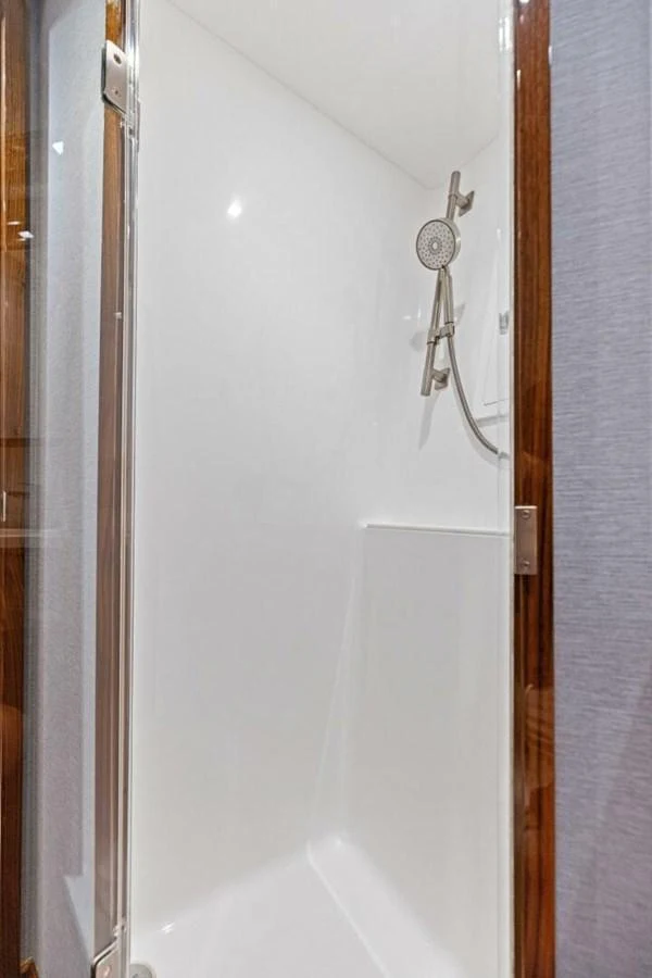 A sleek and modern shower area with a handheld showerhead and clean white surfaces. aboard TEAM HARVEY I Yacht for Sale