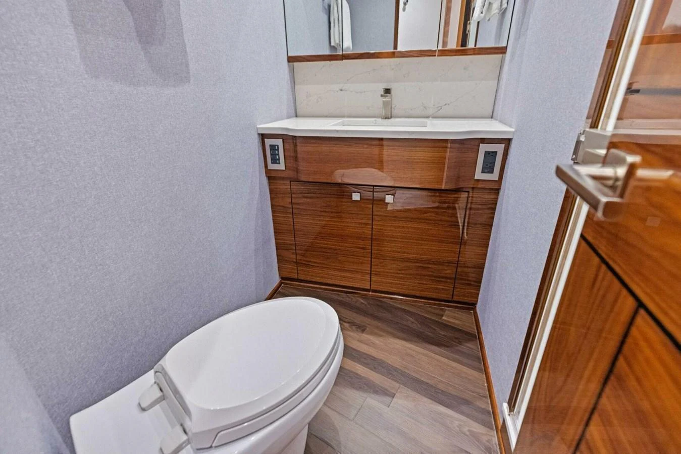 This is a modern yacht bathroom featuring a sleek vanity and a contemporary toilet. aboard TEAM HARVEY I Yacht for Sale