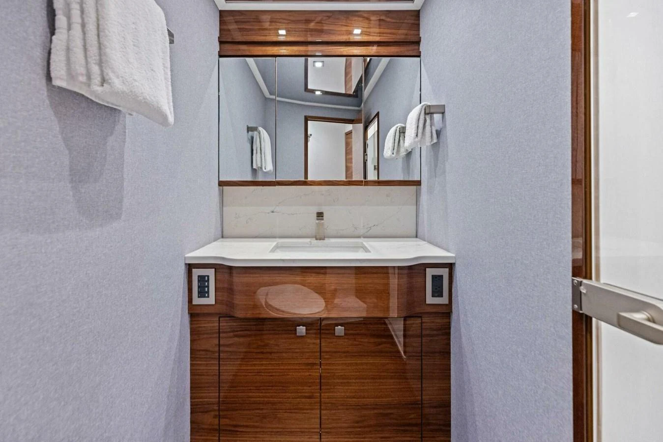 A sleek and modern yacht bathroom with a polished wood vanity and large mirror. aboard TEAM HARVEY I Yacht for Sale