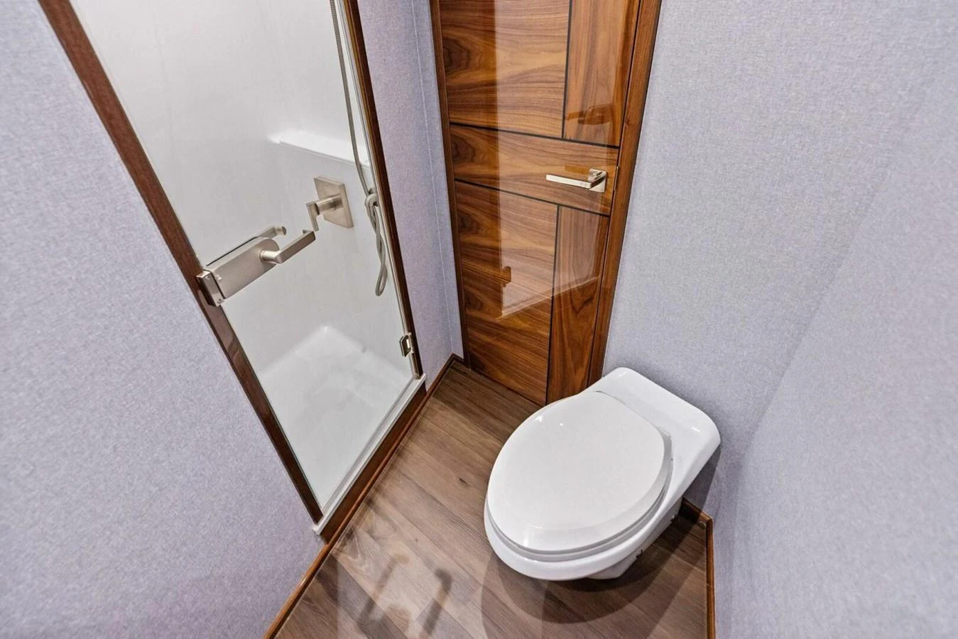 A compact and modern yacht bathroom with a sleek wooden finish and a glass shower enclosure. aboard TEAM HARVEY I Yacht for Sale