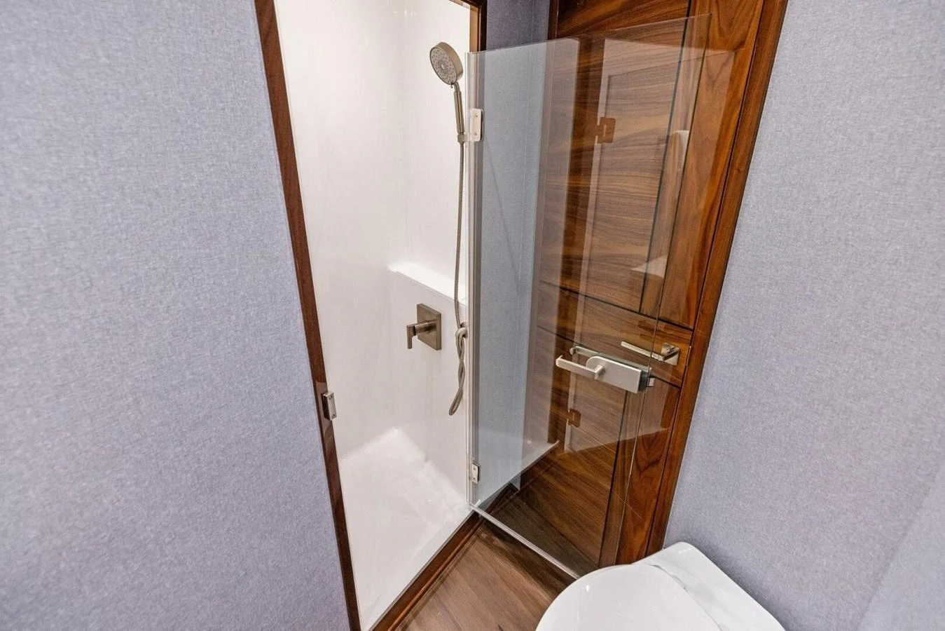 A modern yacht bathroom featuring a sleek shower enclosure with a glass door and wooden accents. aboard TEAM HARVEY I Yacht for Sale