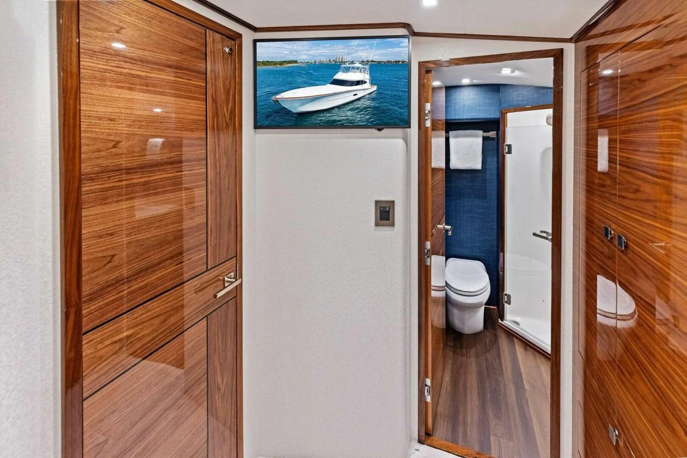 A sleek hallway with polished wood finishes leads to a modern bathroom on a luxury yacht. aboard TEAM HARVEY I Yacht for Sale