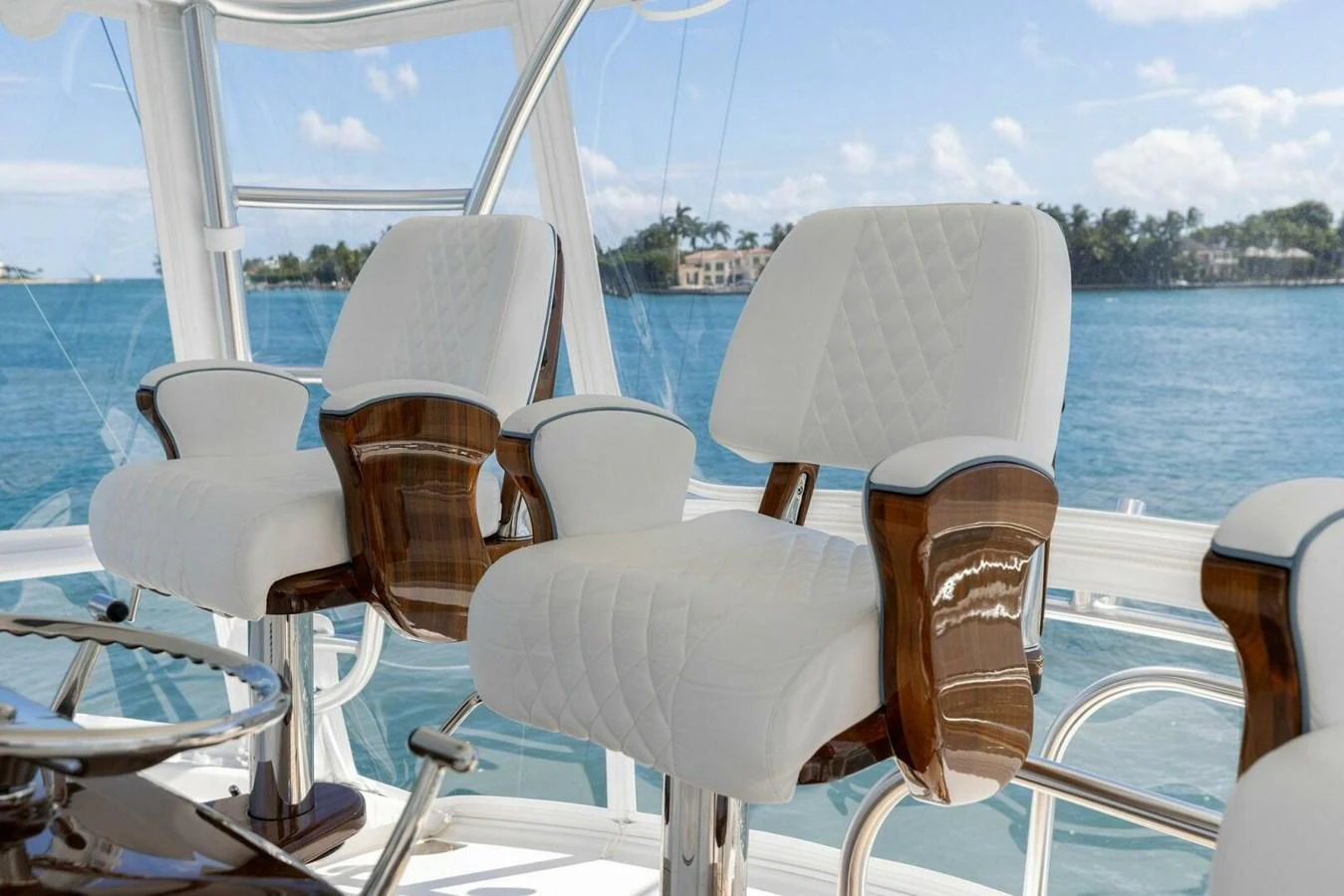 The helm features luxurious white quilted chairs with polished wooden armrests, offering a commanding view of the water. aboard TEAM HARVEY I Yacht for Sale