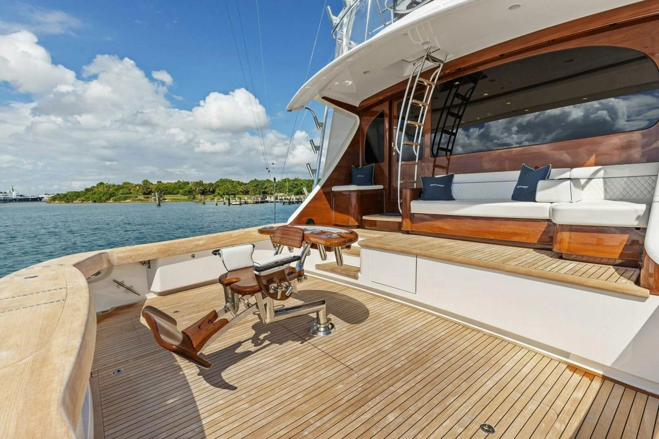 The aft deck features a spacious seating area with luxurious wooden finishes and a fishing chair setup. aboard TEAM HARVEY I Yacht for Sale