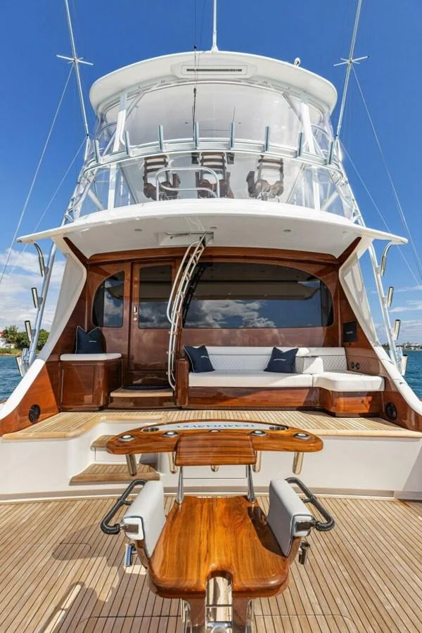The yacht's aft deck features a comfortable seating area with a polished wooden table and chairs, perfect for relaxation and dining. aboard TEAM HARVEY I Yacht for Sale