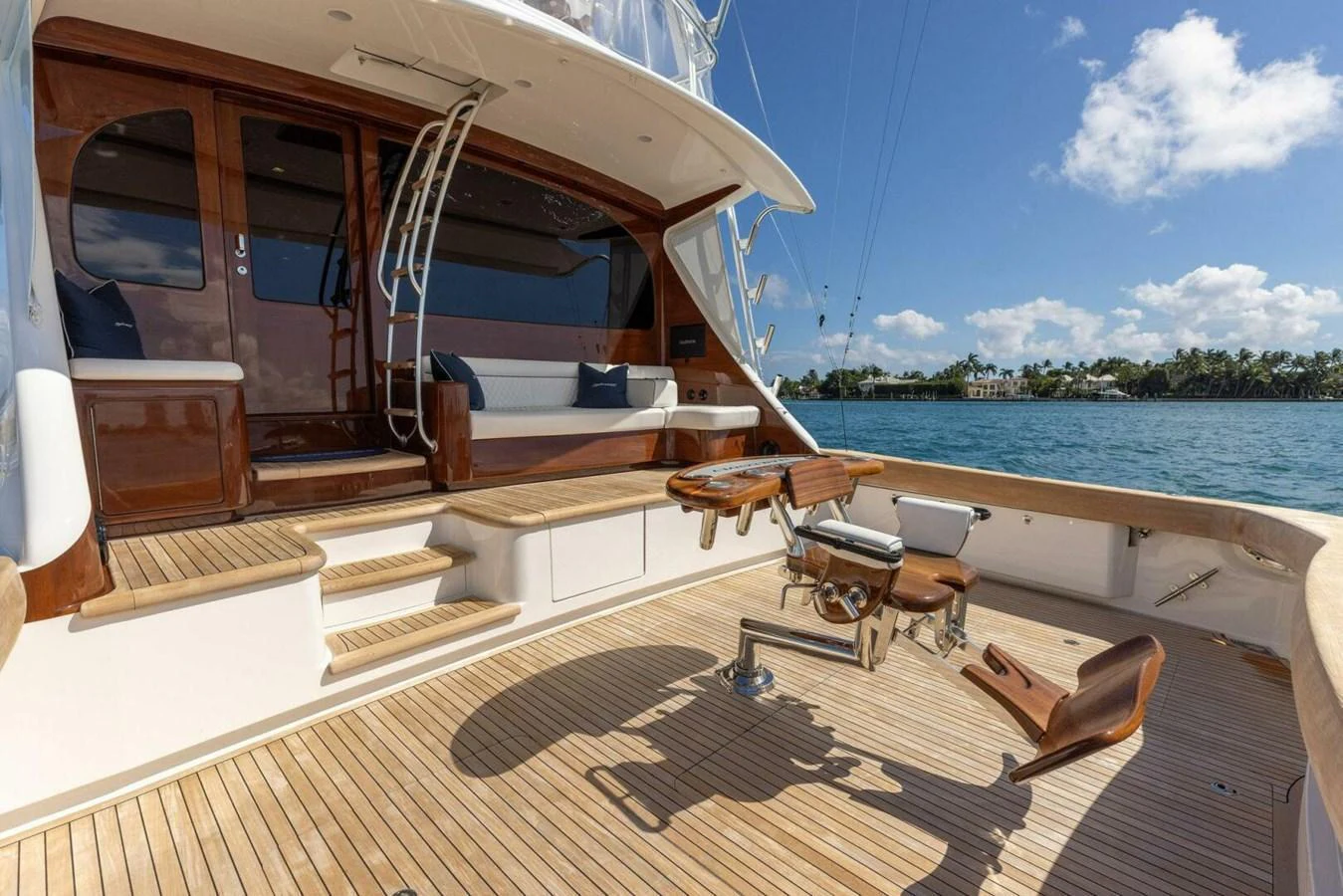 The aft deck features a spacious seating area with polished wood finishes and a scenic view of the water. aboard TEAM HARVEY I Yacht for Sale