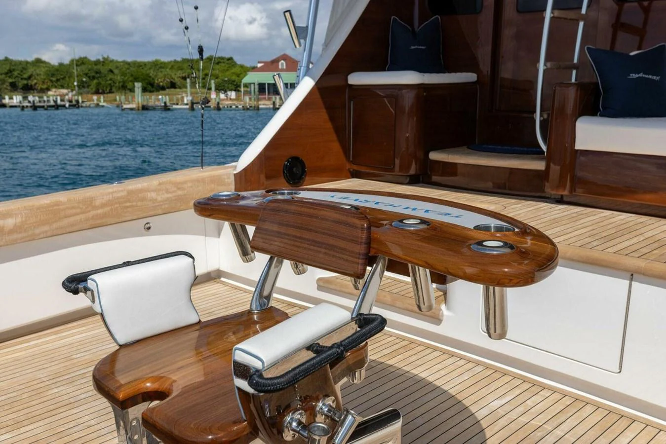 The image showcases a well-equipped fishing station on the yacht's deck, featuring a polished wooden fighting chair and rod holders. aboard TEAM HARVEY I Yacht for Sale