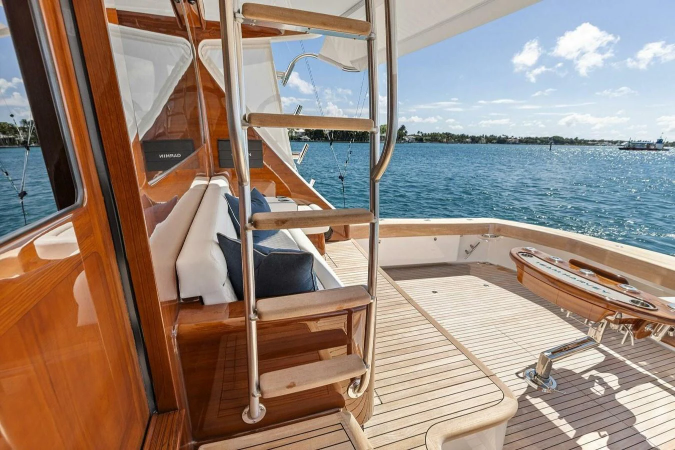 The aft deck features a polished wooden staircase and a comfortable seating area with a stunning view of the water. aboard TEAM HARVEY I Yacht for Sale