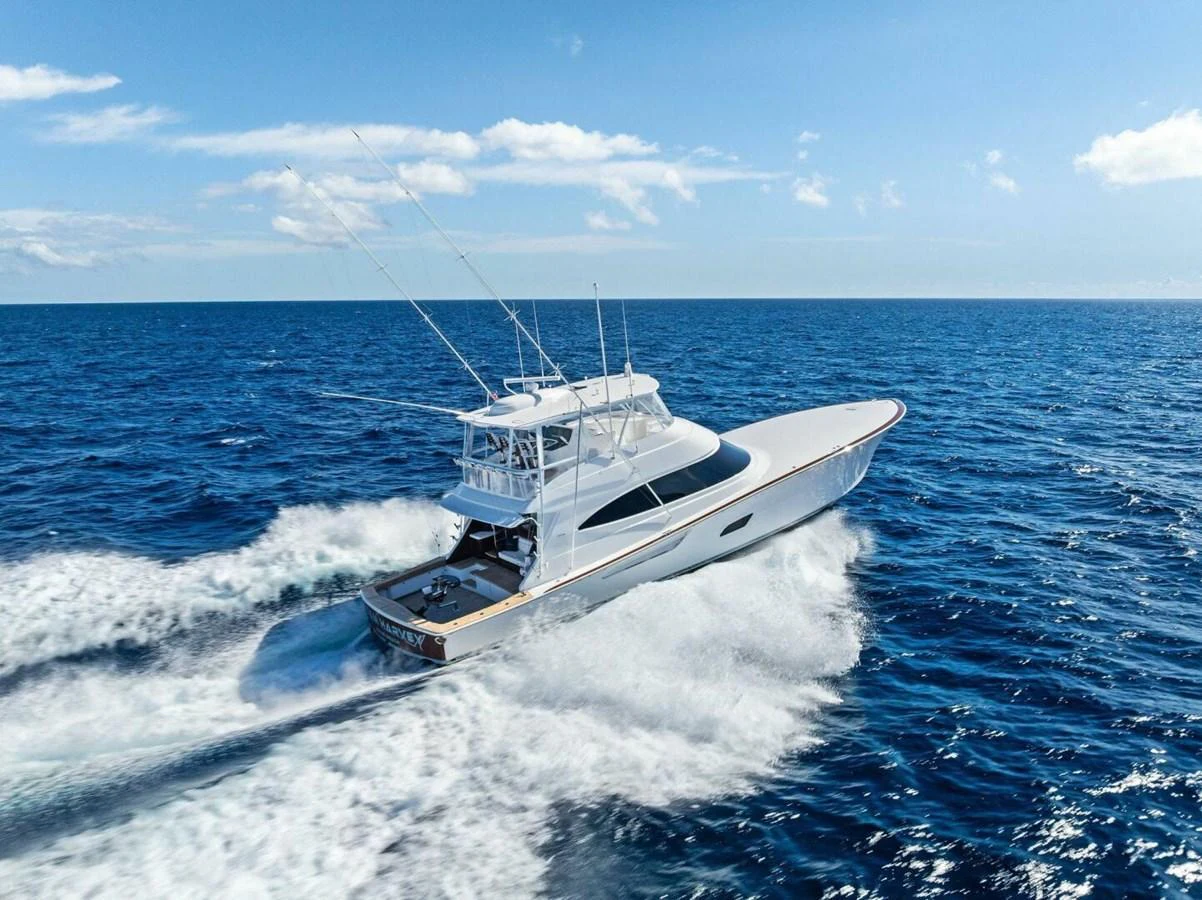 A sleek yacht cruises swiftly through the open sea under a clear blue sky. aboard TEAM HARVEY I Yacht for Sale