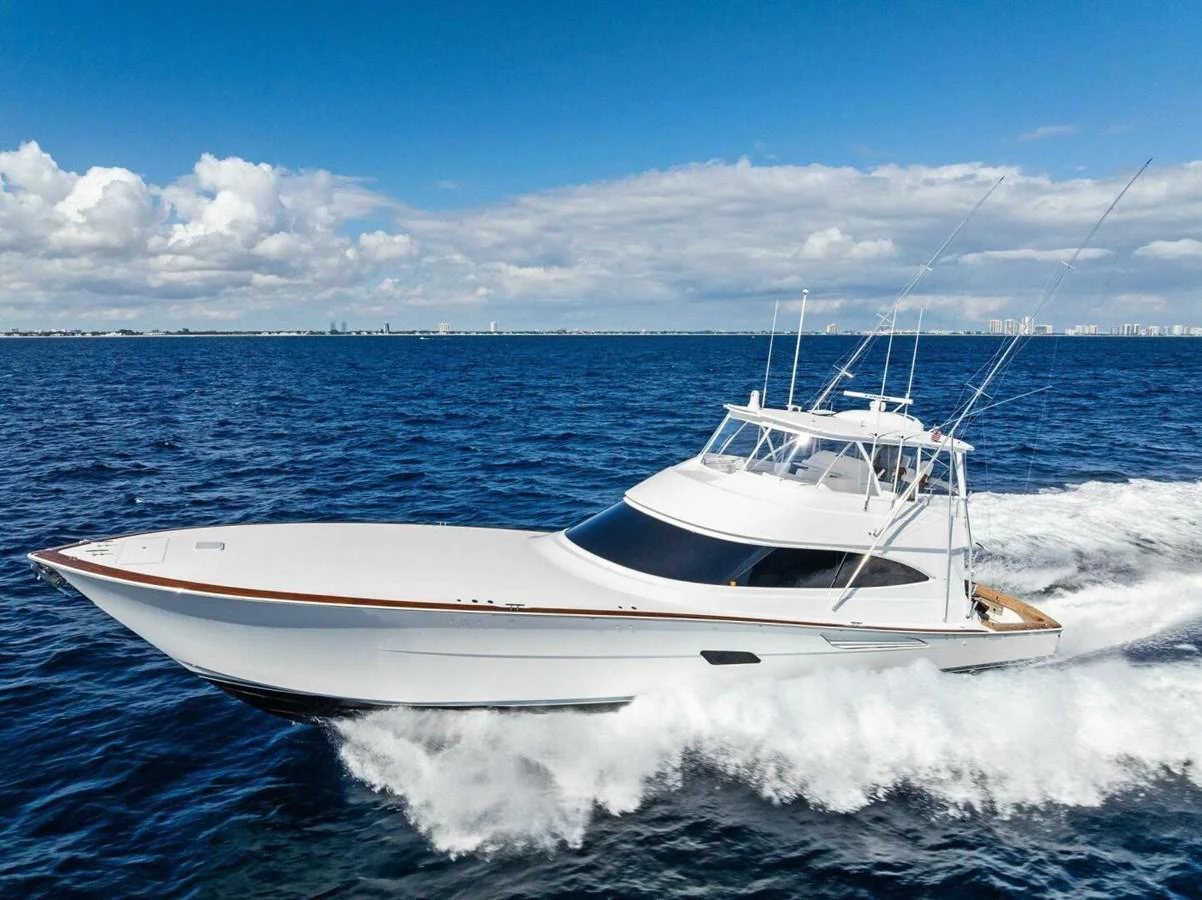 A sleek yacht cruises swiftly on open water under a bright blue sky. aboard TEAM HARVEY I Yacht for Sale