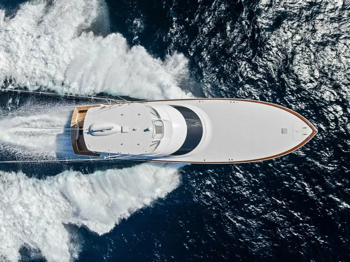 An aerial view of a sleek yacht cruising through the water, leaving a trail of white wake behind. aboard TEAM HARVEY I Yacht for Sale