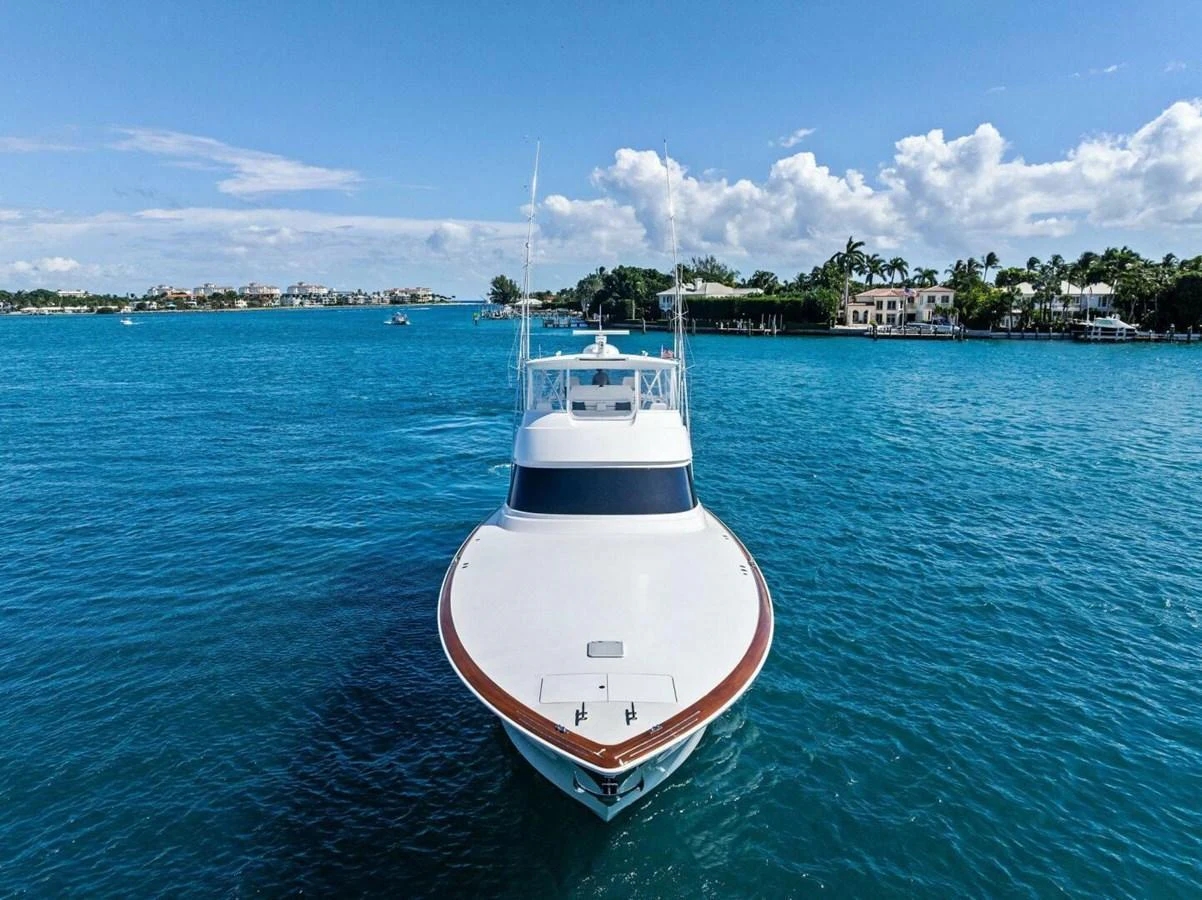 A sleek yacht cruising on clear blue waters with a scenic coastal backdrop. aboard TEAM HARVEY I Yacht for Sale