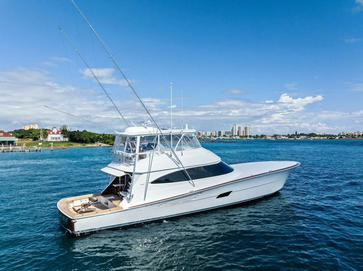 A sleek yacht cruises on calm blue waters under a clear sky, showcasing its elegant design and spacious deck. aboard TEAM HARVEY I Yacht for Sale