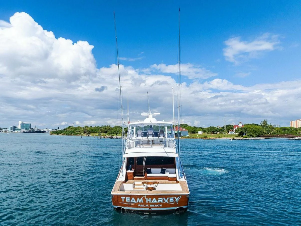 A sleek yacht is seen from the rear, cruising on calm waters under a bright blue sky. aboard TEAM HARVEY I Yacht for Sale