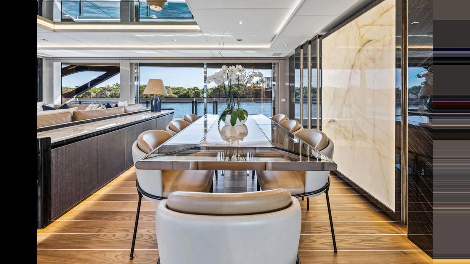 The yacht's dining area features a sleek table with plush seating and expansive windows offering stunning views. aboard ARTEMIS Yacht for Sale