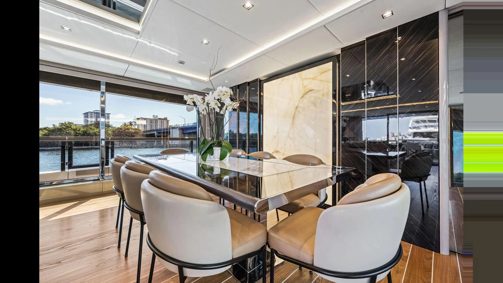 The yacht's dining area features a sleek table surrounded by plush chairs, with large windows offering a scenic view. aboard ARTEMIS Yacht for Sale