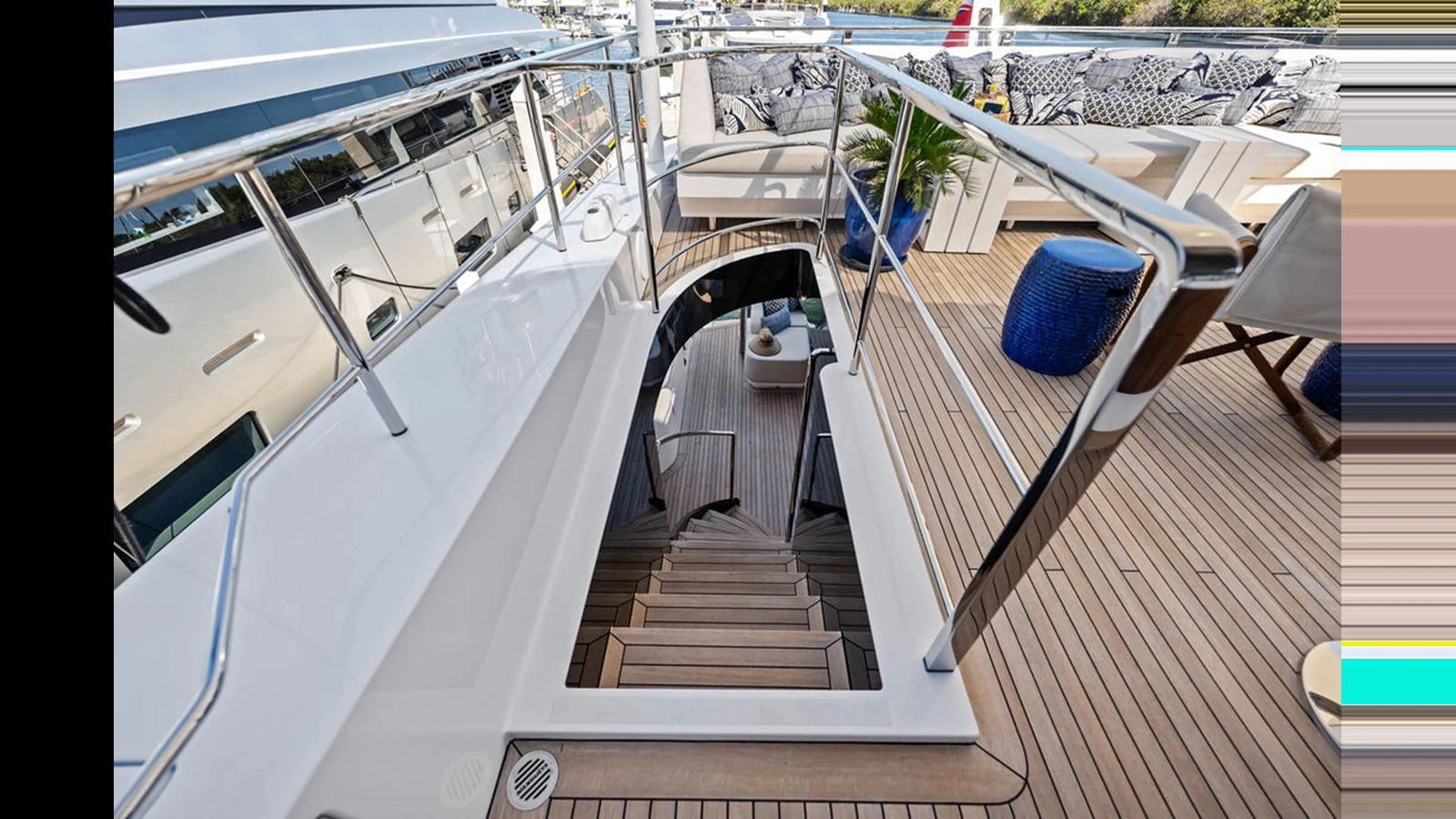 The yacht's deck features a stylish staircase leading to the lower level, surrounded by comfortable seating and modern decor. aboard ARTEMIS Yacht for Sale