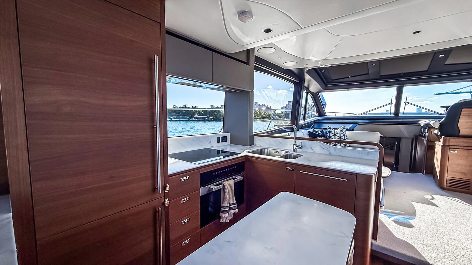 The yacht's galley features sleek wooden cabinetry and modern appliances with a view of the water through large windows. aboard NAUTILUS Yacht for Sale
