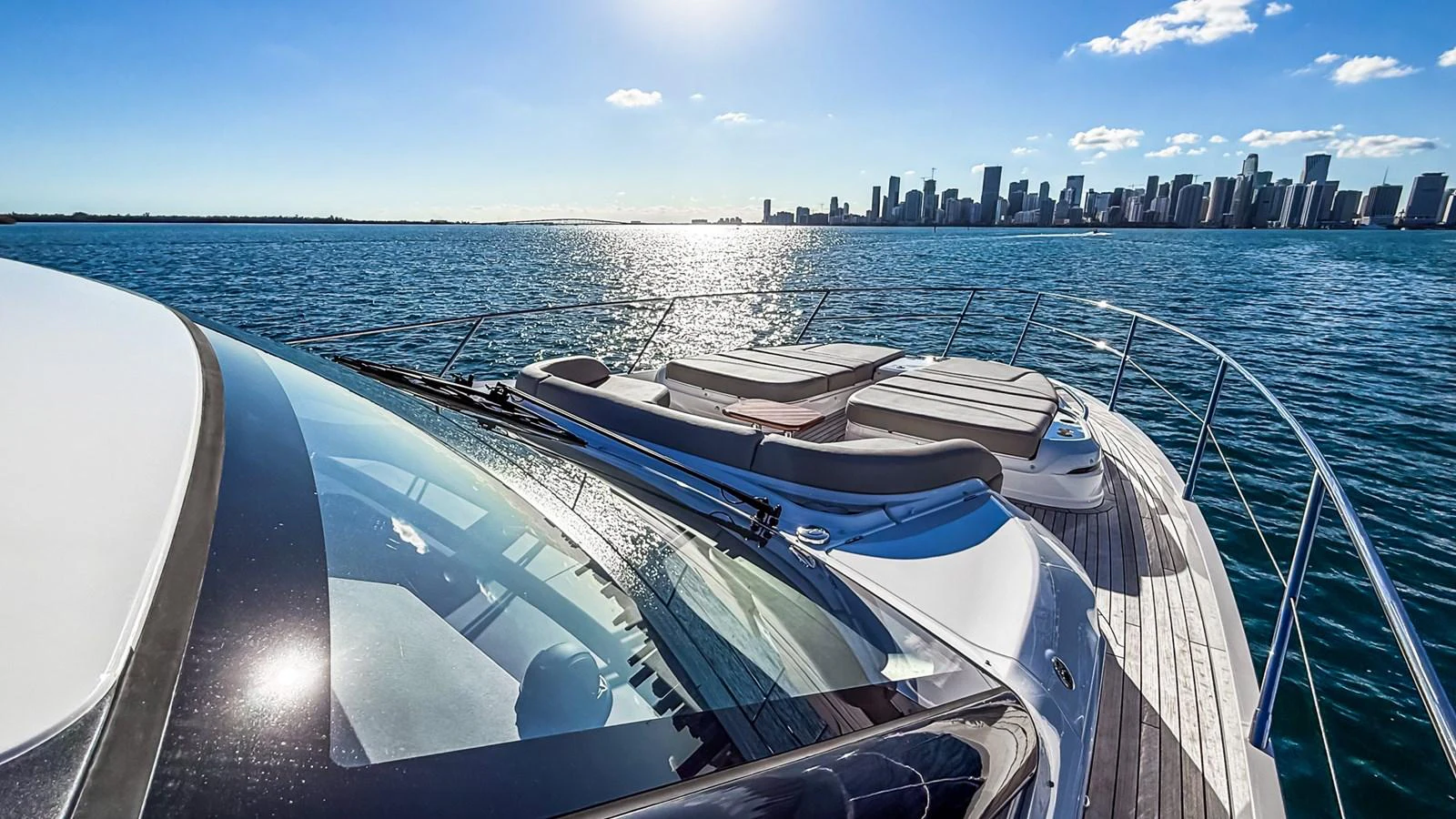 The yacht's foredeck offers a luxurious sunbathing area with a stunning city skyline in the background. aboard NAUTILUS Yacht for Sale