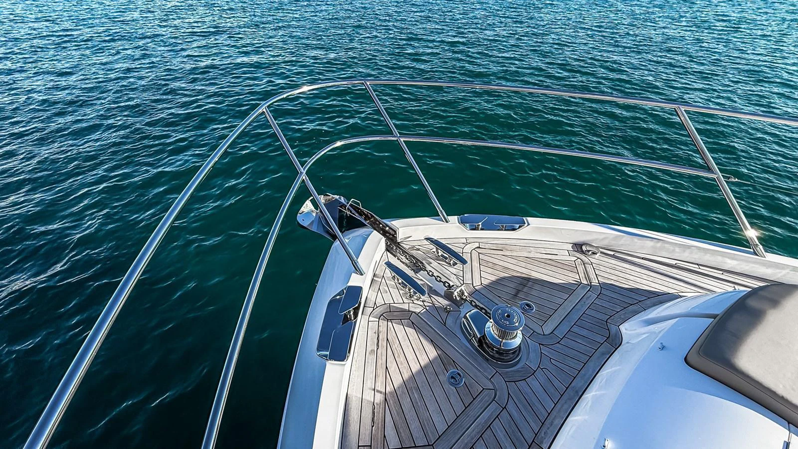 The bow of the yacht features sleek stainless steel railings and a well-maintained teak deck, set against the backdrop of clear blue waters. aboard NAUTILUS Yacht for Sale