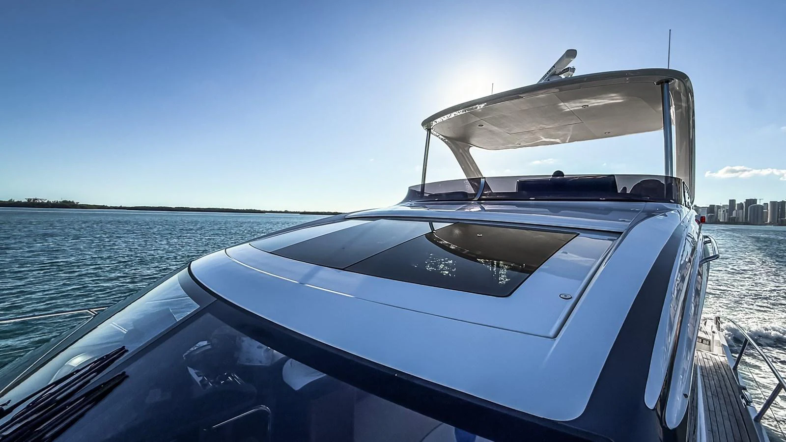 A sleek yacht glides through the water under a clear blue sky, showcasing its modern design and spacious deck. aboard NAUTILUS Yacht for Sale