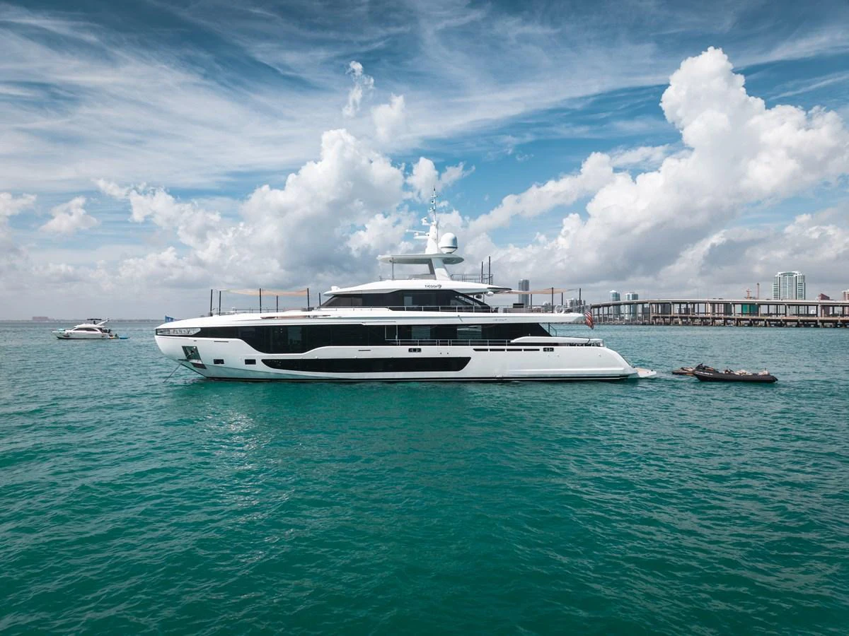 A sleek and modern yacht glides gracefully on the open water under a partly cloudy sky. aboard TYCOON Yacht for Sale