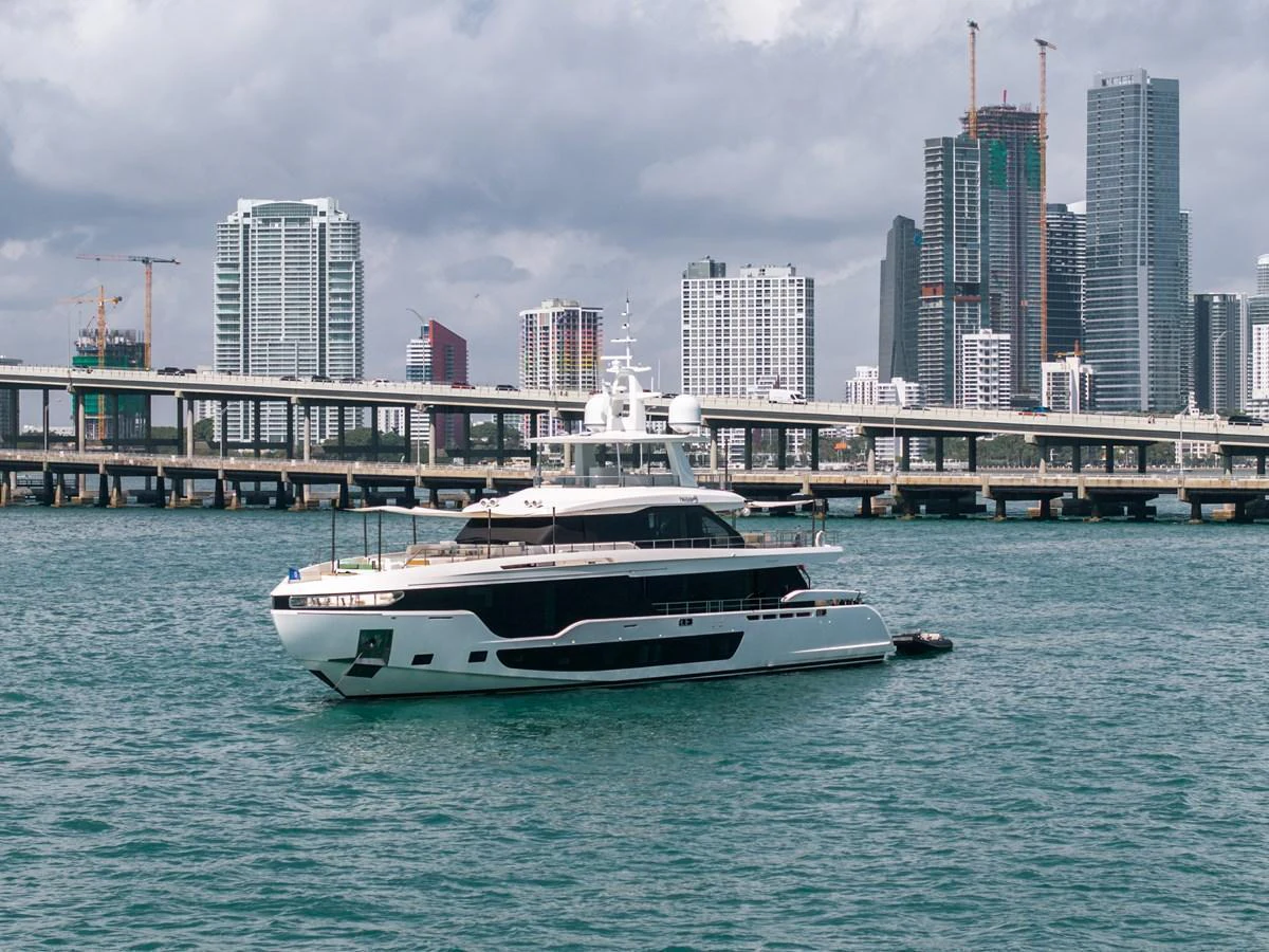A sleek and modern yacht cruises in front of a vibrant city skyline. aboard TYCOON Yacht for Sale