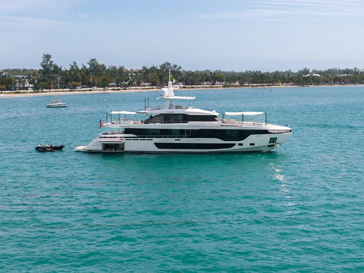 A sleek and modern yacht cruising in clear turquoise waters near a scenic coastline. aboard TYCOON Yacht for Sale
