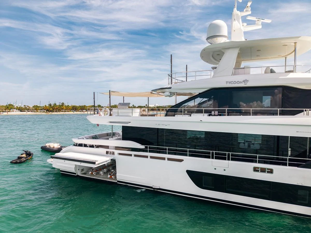 A sleek and modern yacht is anchored in clear turquoise waters, showcasing its luxurious design and amenities. aboard TYCOON Yacht for Sale