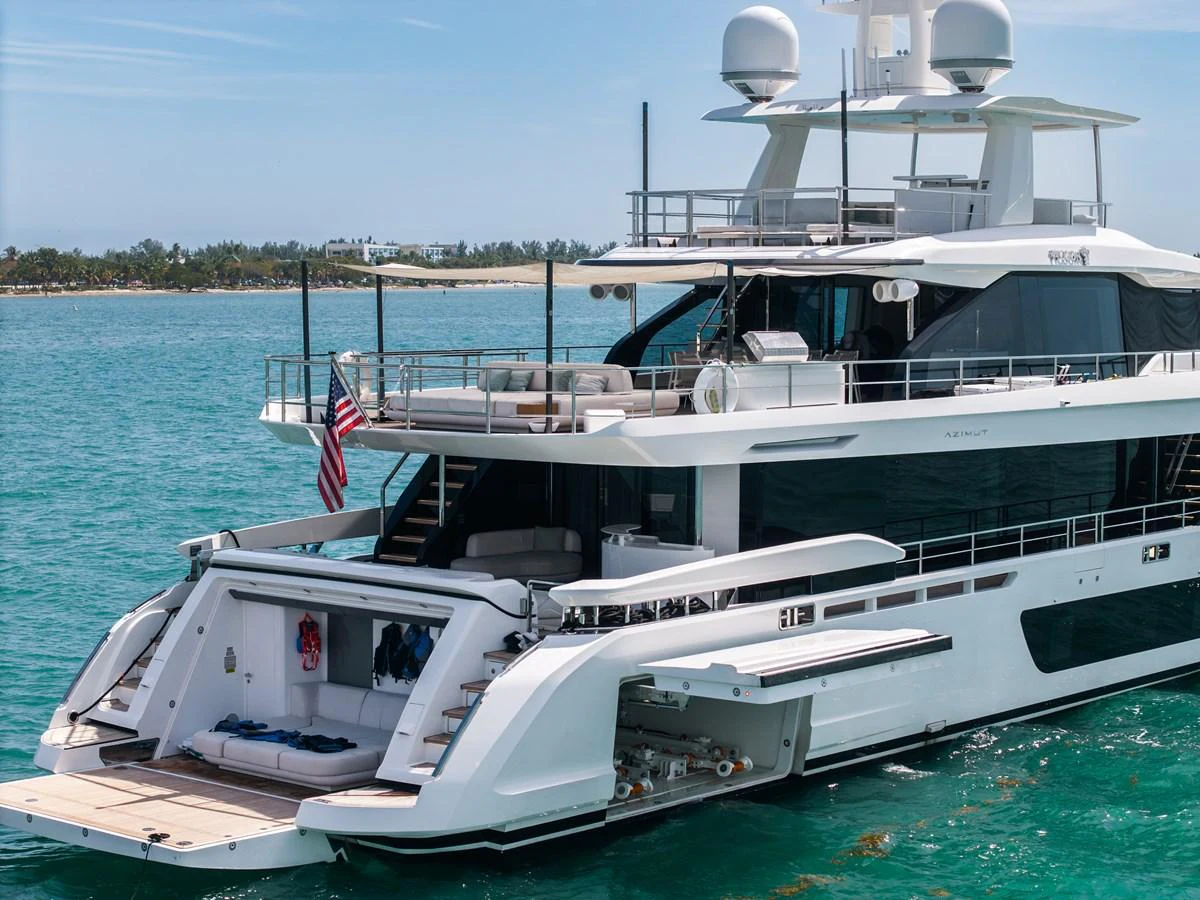 A luxurious yacht with an inviting aft deck is anchored in clear blue waters. aboard TYCOON Yacht for Sale