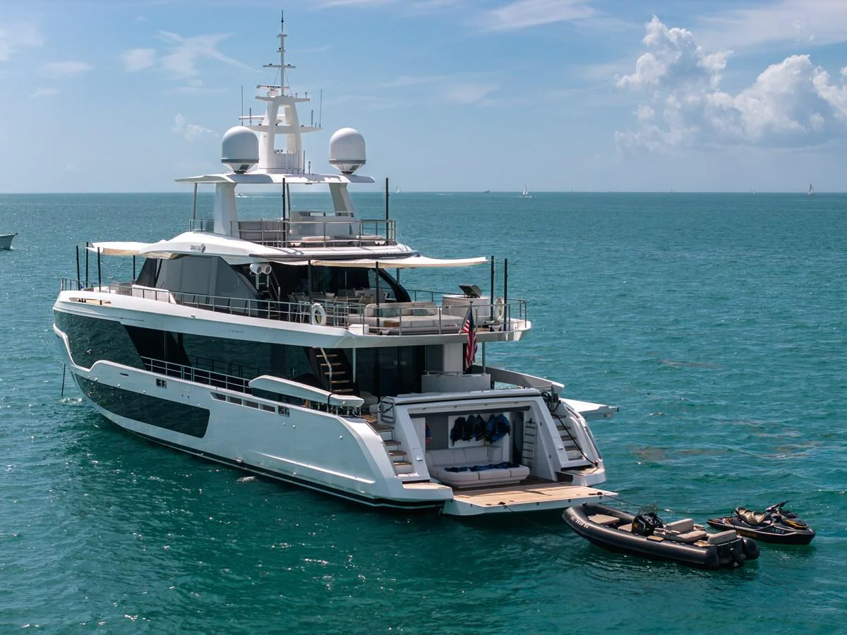 A luxurious yacht anchored in serene blue waters, showcasing its spacious aft deck and tender boats. aboard TYCOON Yacht for Sale