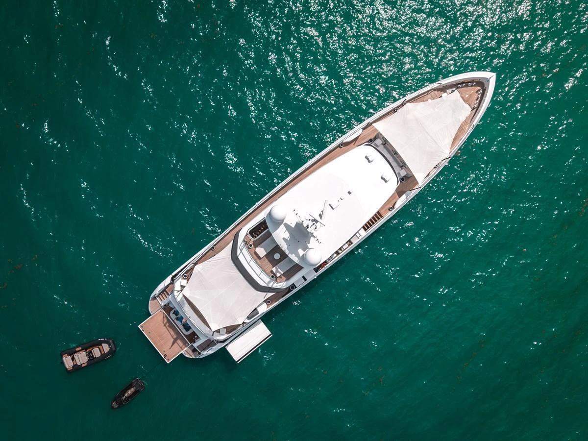 Aerial view of a luxurious yacht anchored in clear turquoise waters, showcasing its sleek design and spacious decks. aboard TYCOON Yacht for Sale