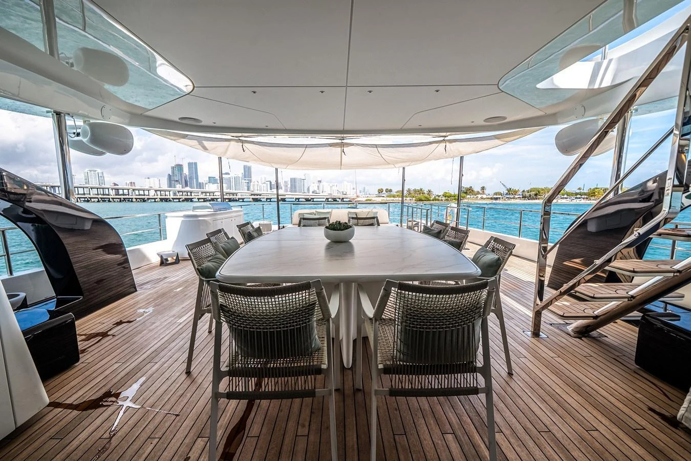 The aft deck features a spacious dining area with a stunning view of the water and city skyline. aboard TYCOON Yacht for Sale