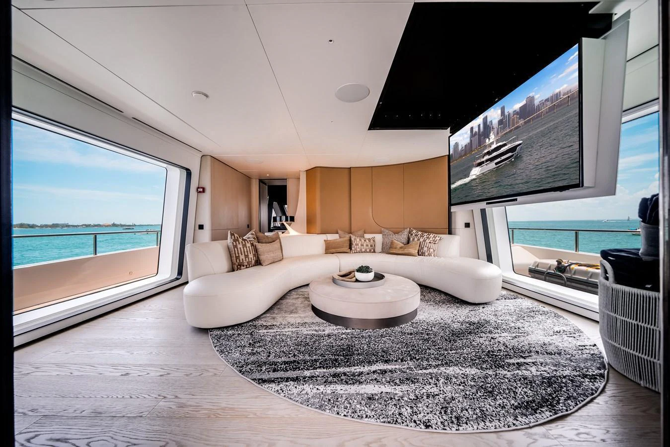 The salon features a modern, curved sofa with panoramic windows offering stunning ocean views. aboard TYCOON Yacht for Sale