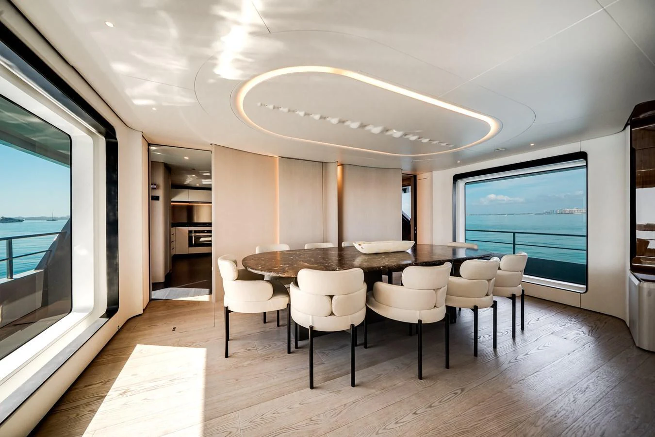 The yacht's dining area features a large round table surrounded by plush chairs, with expansive windows offering stunning ocean views. aboard TYCOON Yacht for Sale