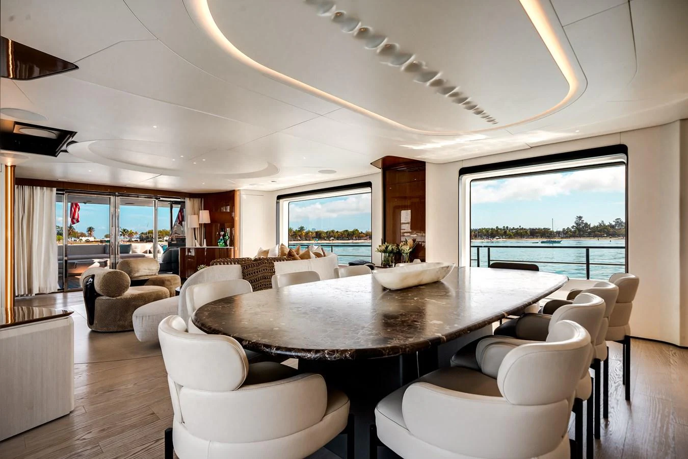 The yacht's dining area features a large table with plush seating, offering panoramic views through expansive windows. aboard TYCOON Yacht for Sale