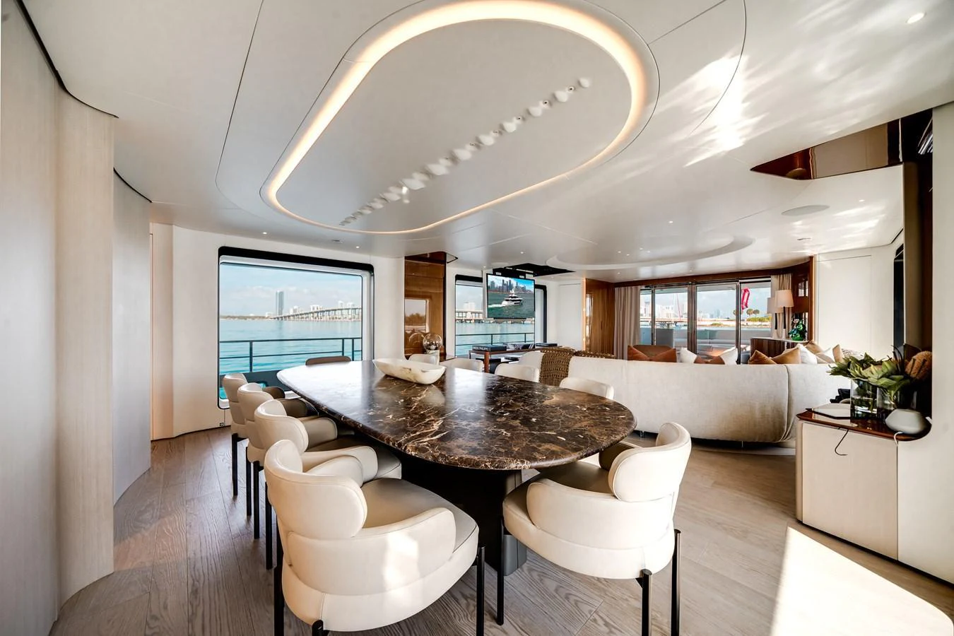 The salon features a luxurious dining area with a marble table and plush seating, complemented by panoramic windows offering stunning views. aboard TYCOON Yacht for Sale
