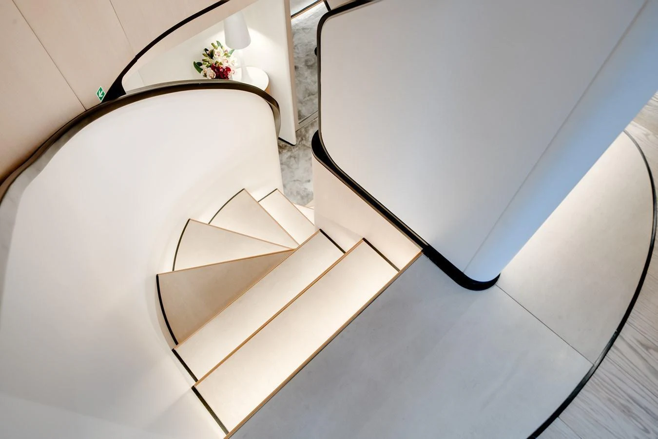A beautifully designed interior staircase with elegant curves and soft lighting. aboard TYCOON Yacht for Sale