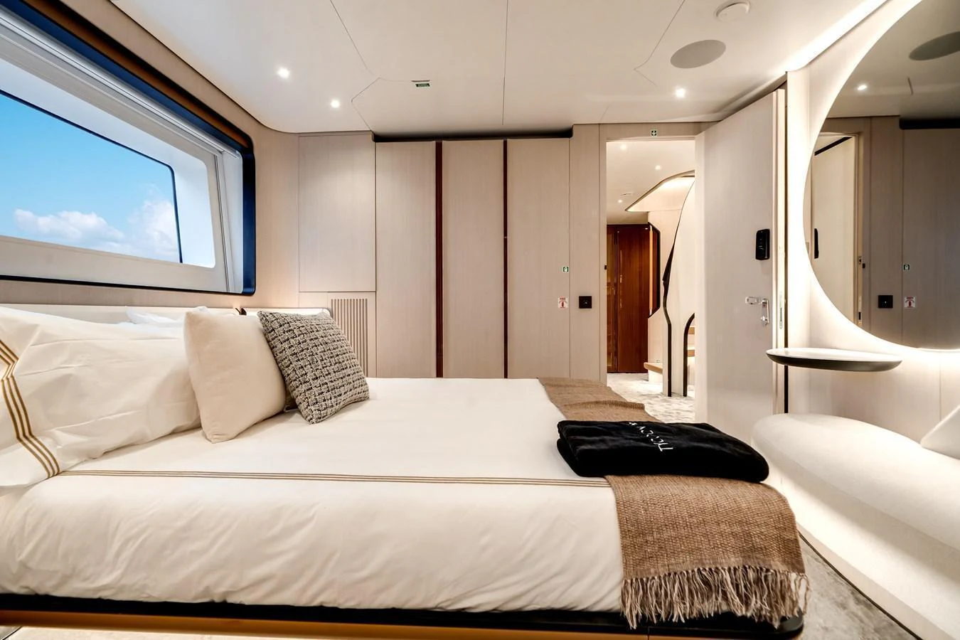 The stateroom features a luxurious bed with elegant linens and a large window offering a scenic view. aboard TYCOON Yacht for Sale