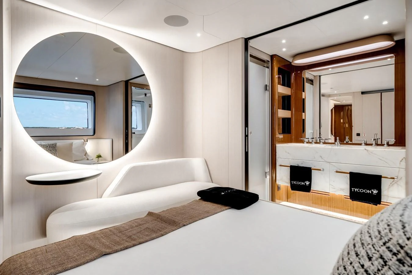 A luxurious stateroom featuring a modern design with a large circular mirror and an ensuite bathroom. aboard TYCOON Yacht for Sale