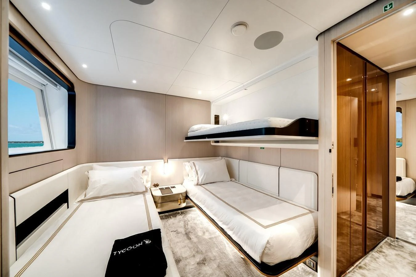 A modern guest cabin featuring twin beds and a bunk bed with elegant decor and ample natural light. aboard TYCOON Yacht for Sale