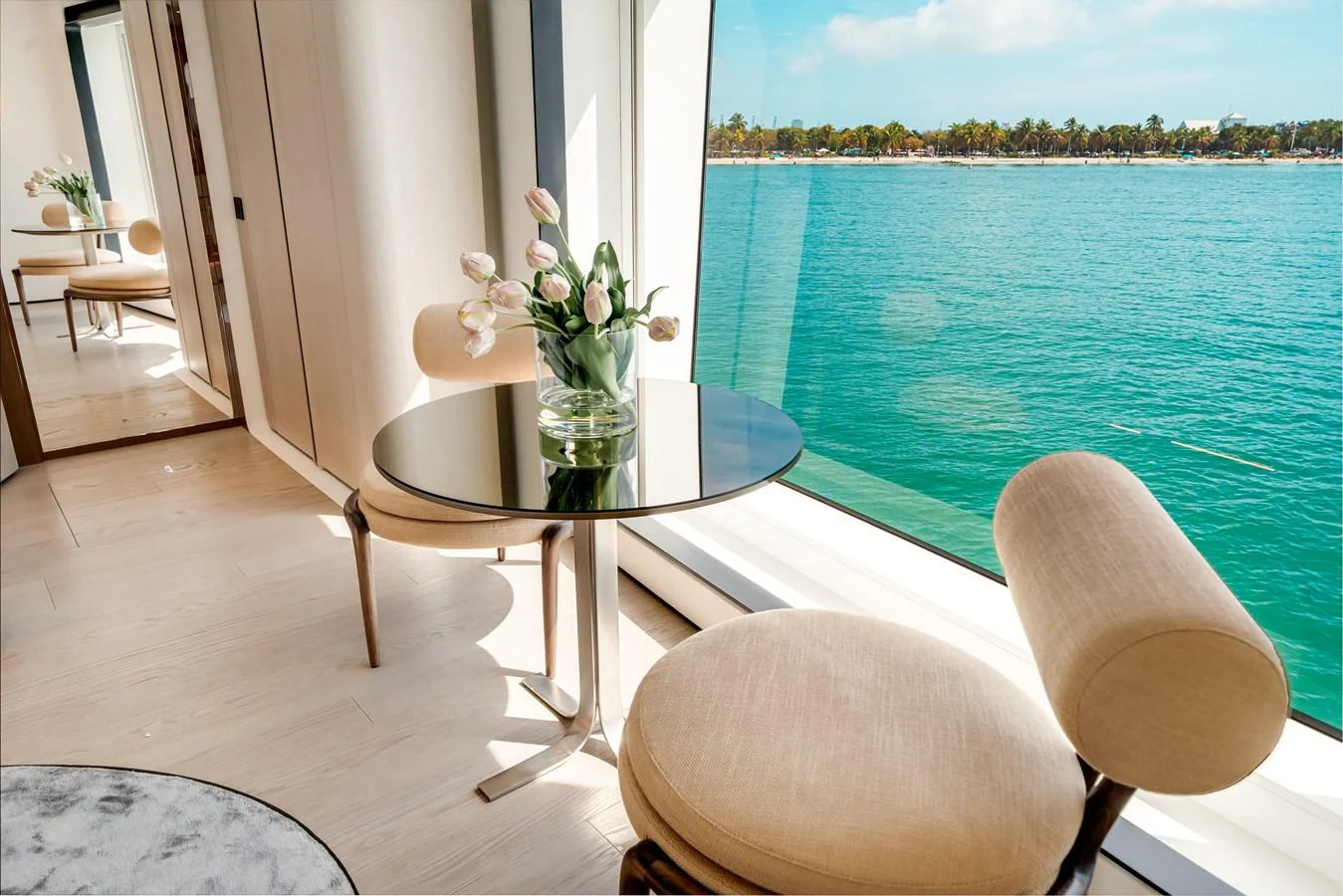 A serene seating area with a round table and two chairs, offering a stunning view of the water through large windows. aboard TYCOON Yacht for Sale