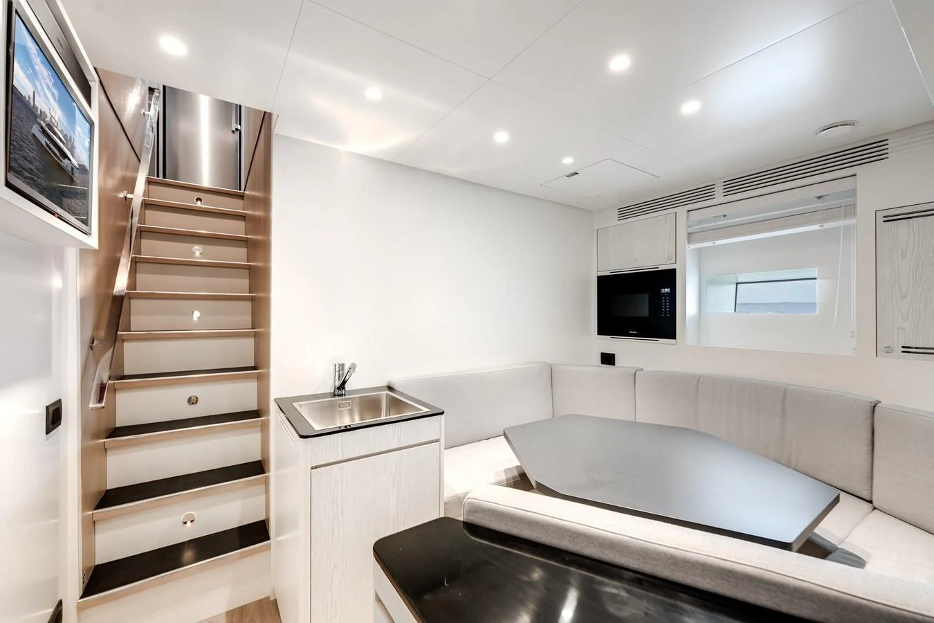 The saloon features a cozy seating area with a modern design and a staircase leading to the upper deck. aboard TYCOON Yacht for Sale
